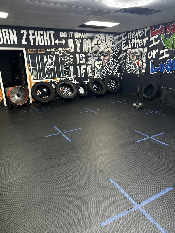 The gym's hand-painted typographic wall, dense with motivational phrases including 'Born 2 Fight,' 'Hustle Is Life,' and 'I never lose — either I WIN or I LEARN'